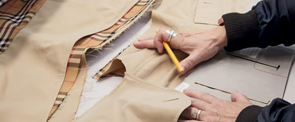 A pair of hands working with pieces of Burberry fabric